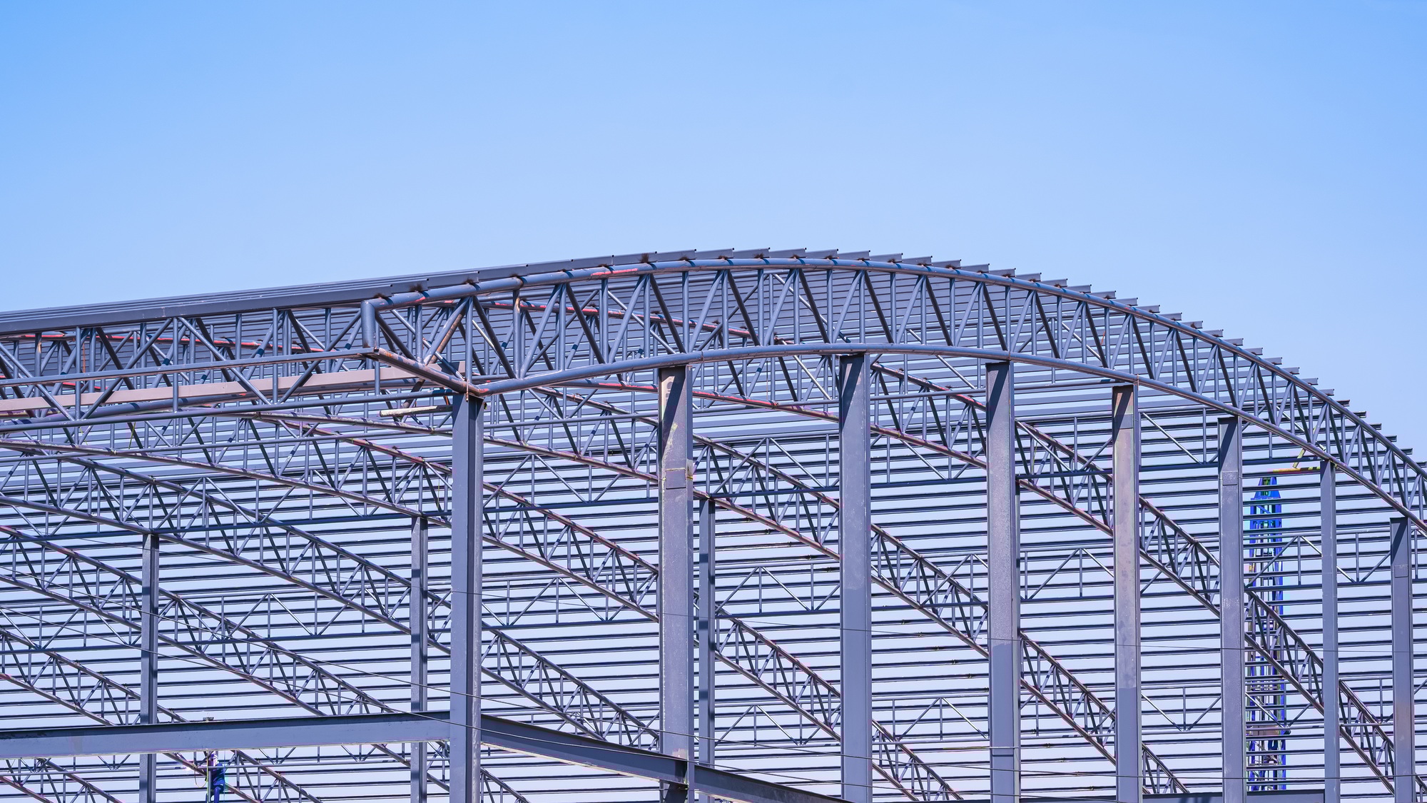 Metal curve roof beam and columns outline of industrial building structure in construction site