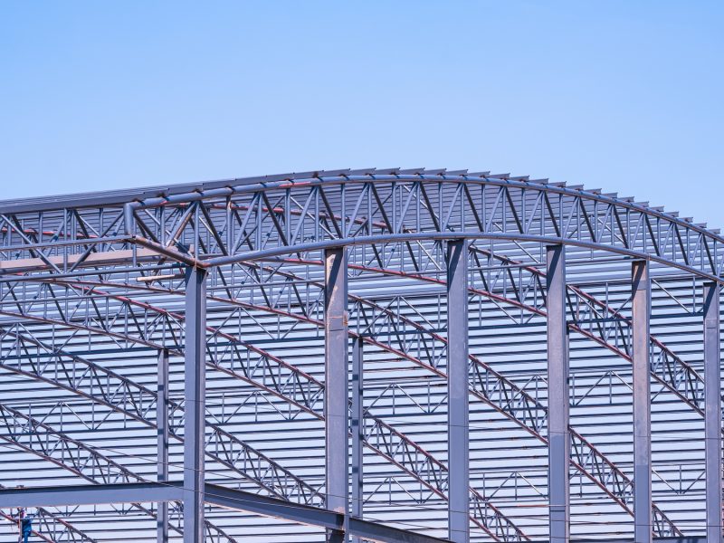 Metal curve roof beam and columns outline of industrial building structure in construction site
