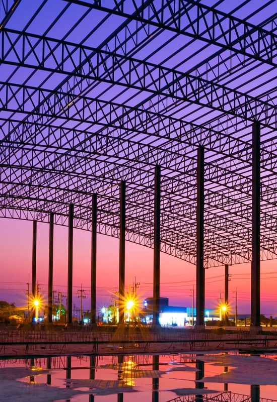 Silhouette large factory building outline structure in construction site against twilight sky